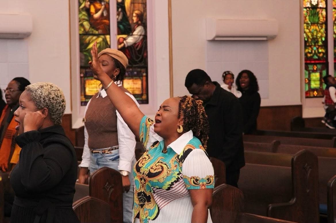 The congregation in worship beneath the stained glass